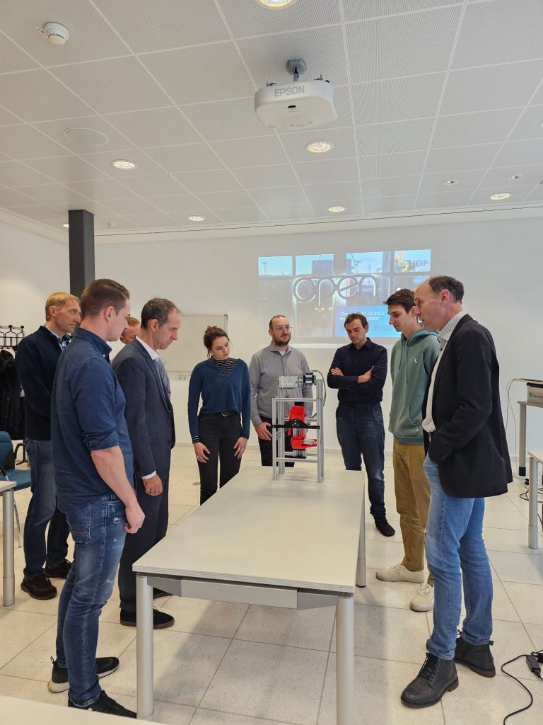 Das OSHOP Team steht versammelt um den Demonstrator, den Valentin erklärt